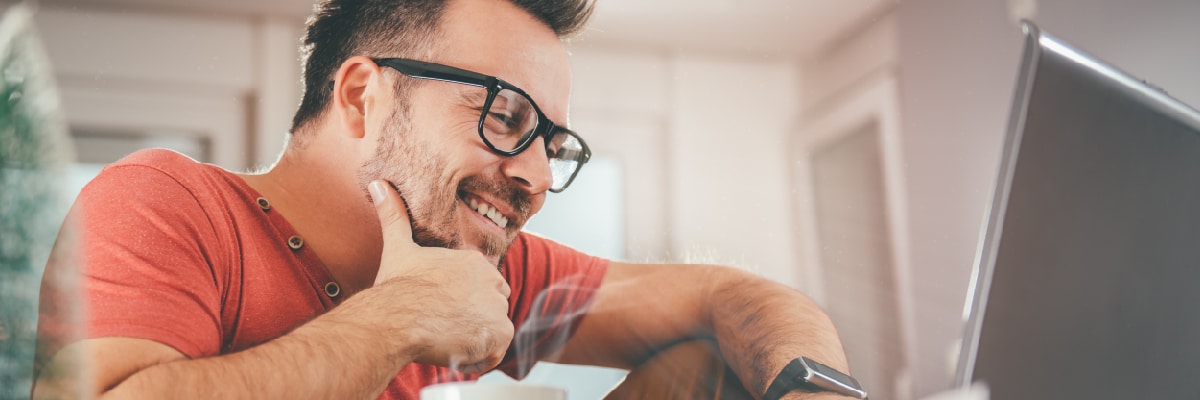 Man With Hand on Chin Smiling While Looking At a Computer