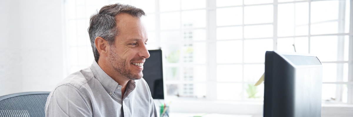 Man Smiling In His Office While at a Computer