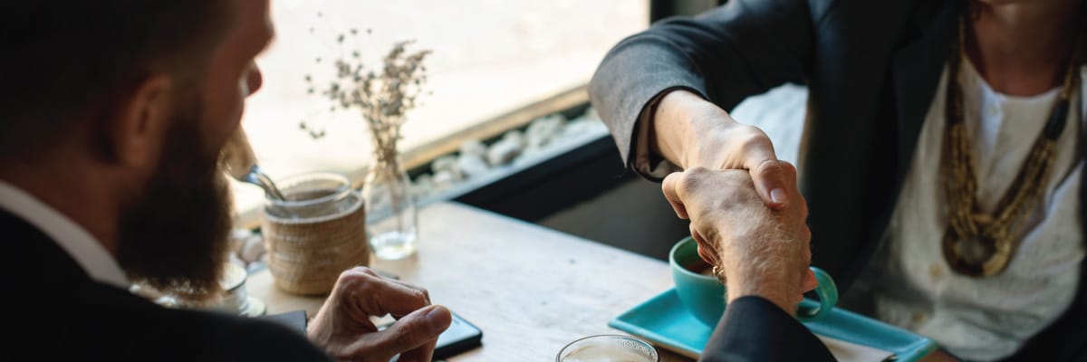 Man Shaking Hands With Woman Over Coffee