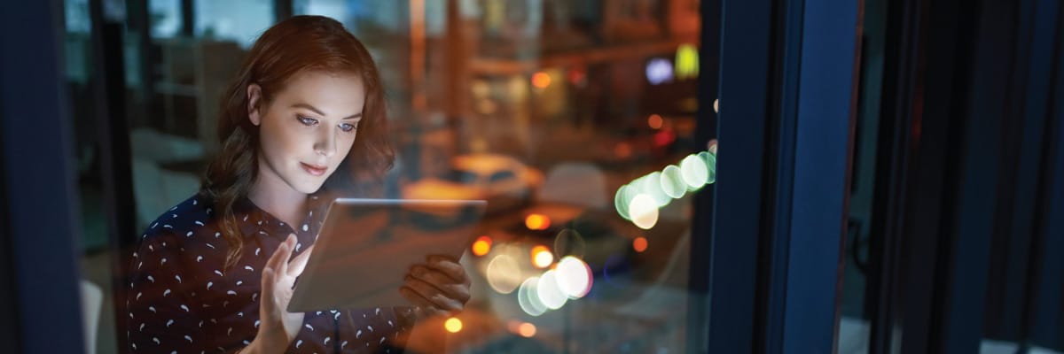 Woman Can be Seen Through Window Using a Tablet