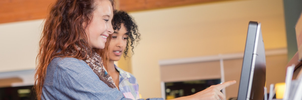 Pair of Young Women Using a Computer Touch Screen