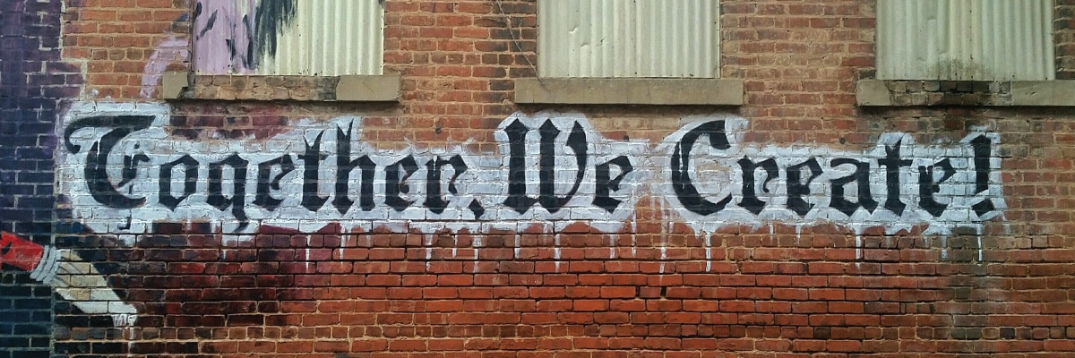 Graffiti on Brick Wall Reading Together We Create