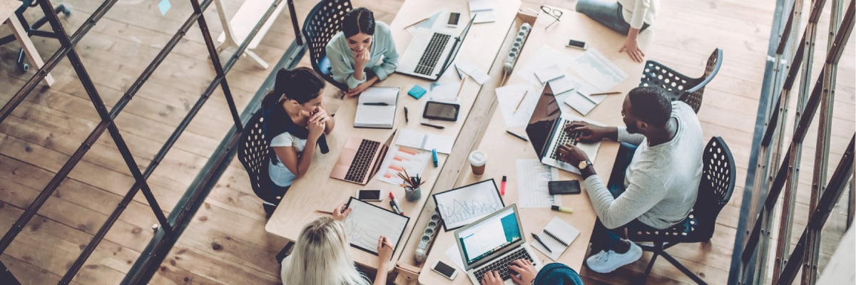 Aerial View of Table With People Working on Various Tech Devices