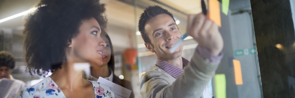 Man Writing on Sticky Note While Woman Watches