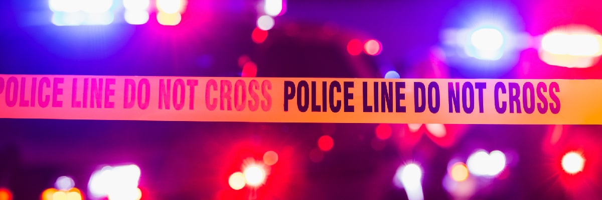 Police Tape with Flashing Lights in Background
