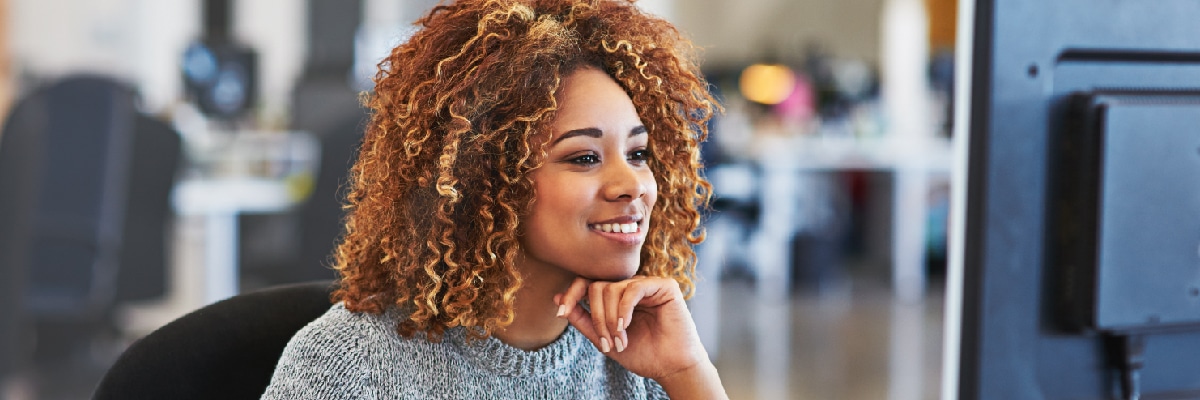 Business Woman Smiling While Looking at Computer Monitor