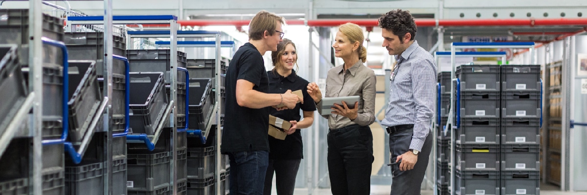 People in Fulfillment Center Discussing Data on a Tablet
