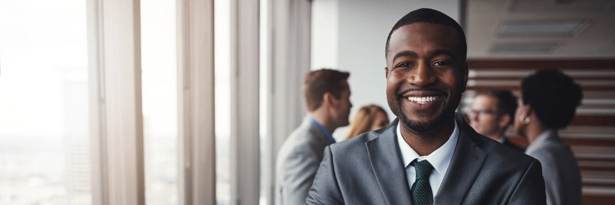 Man in Suit Smiling with Group of Out of Focus People Talking in Background
