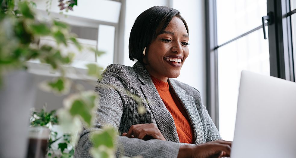 Image shows a smiling professional woman  working on her laptop.