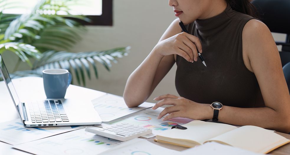 Image shows a professional woman working on her laptop.