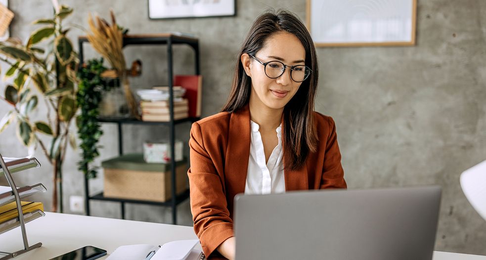 Image shows a professional woman working on her laptop.