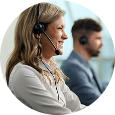 A woman with a headset is smiling in a call-center setting.