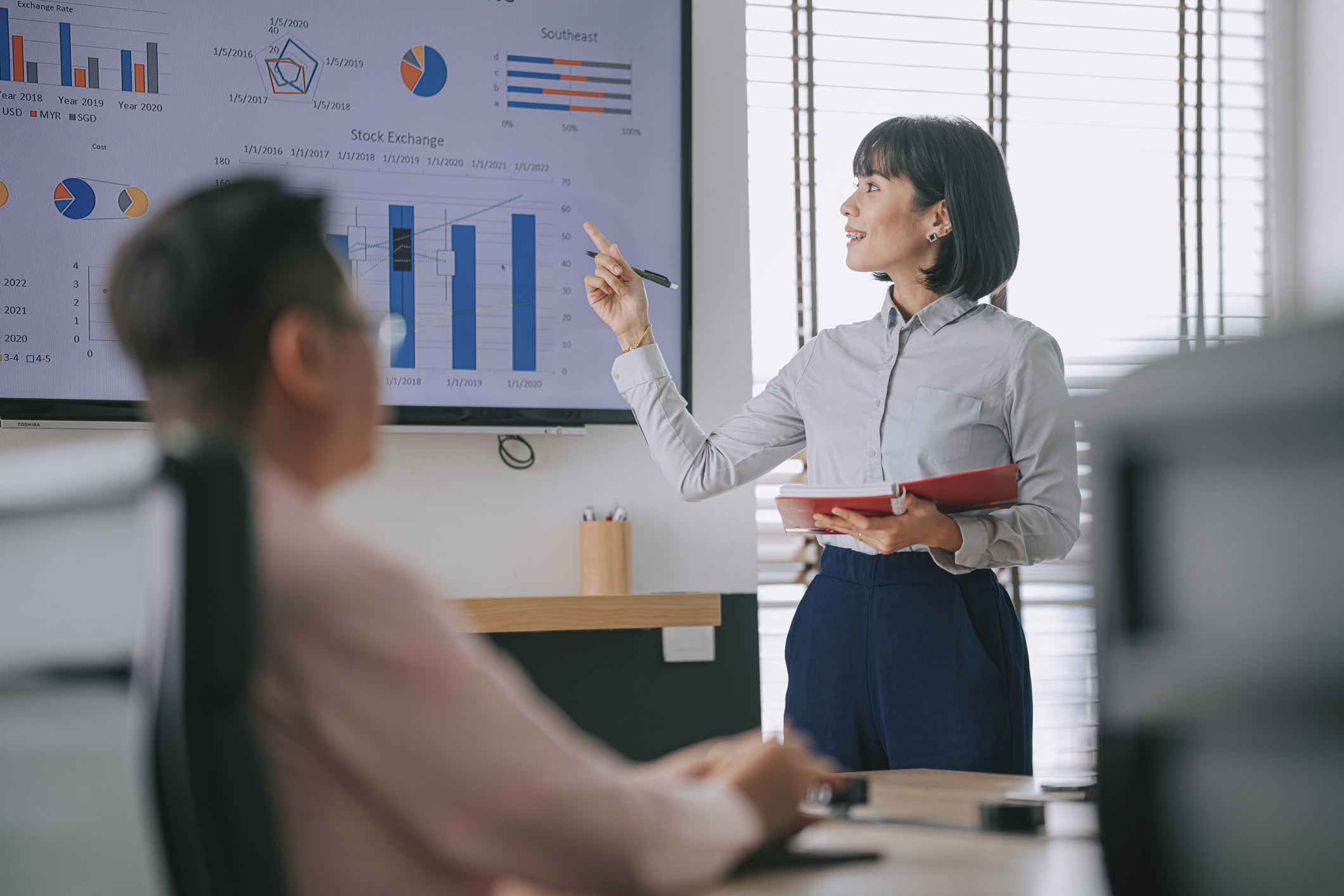A corporate trainer presenting training and development metrics on a data dashboard to an employee during a corporate learning session.